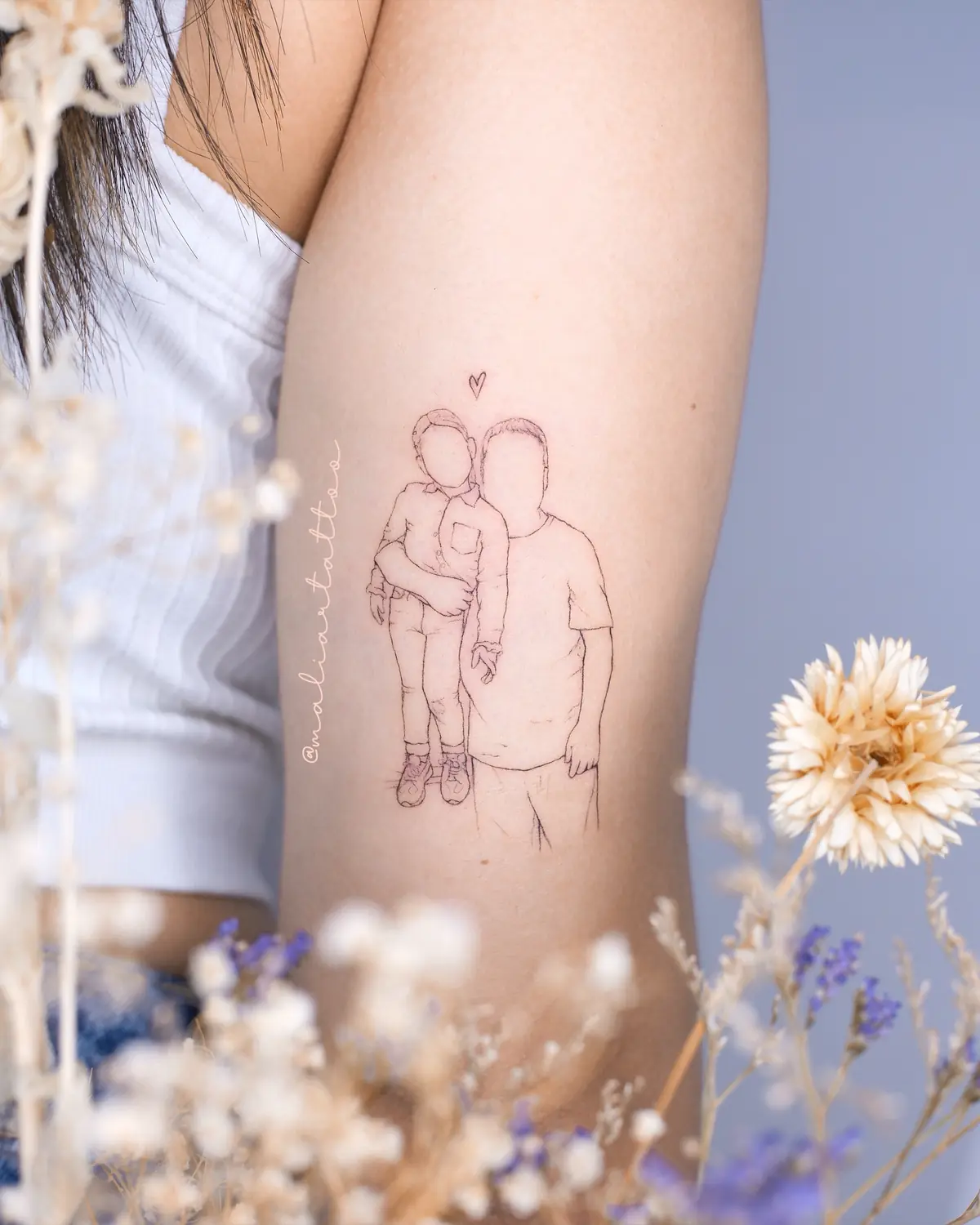 Abrazo, tatuaje de línea fina en brazo