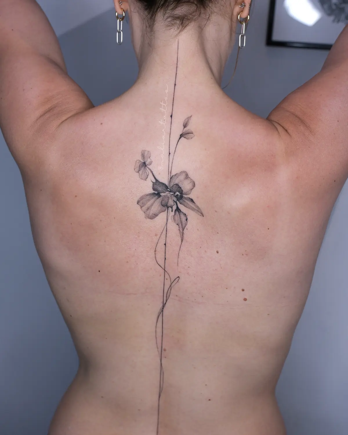 Flor en la columna, tatuaje de línea fina, botánica en espalda
