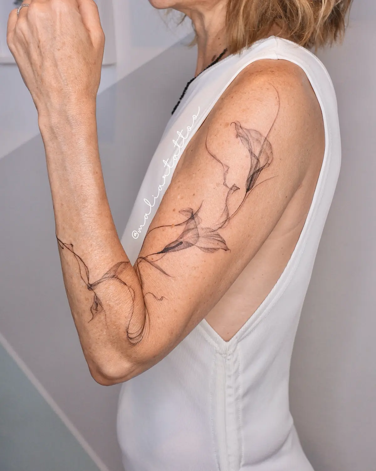 Trazos fluidos, tatuaje de línea fina, botánica en brazo